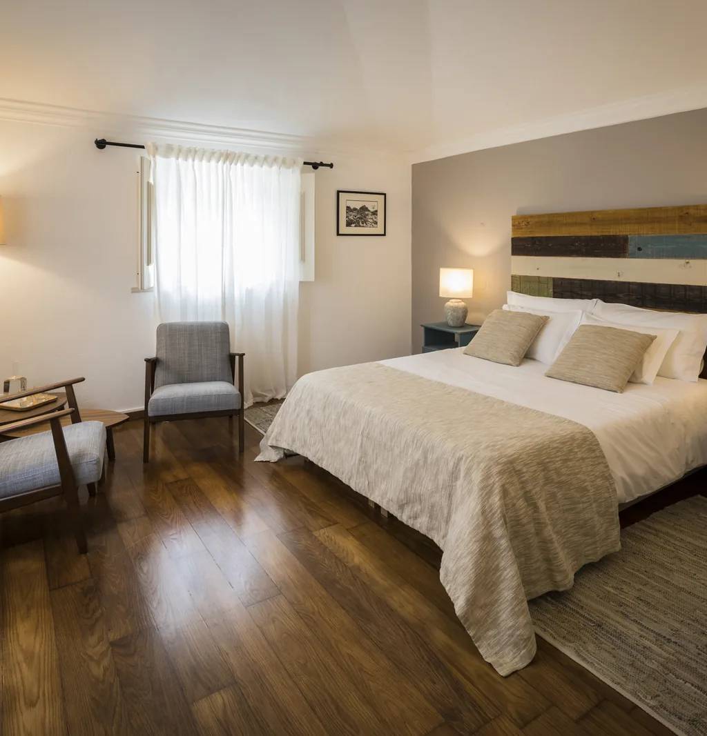 Quarto Regaleira da Quinta do Pé Descalço em Sintra, com cama de casal e cabeceira em madeira recuperada, para quem fica alojado.