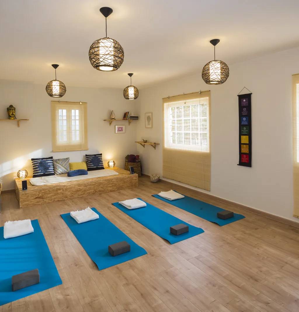Sala de yoga da Quinta do Pé Descalço em Sintra, com quatro tapetes preparados e luz natural.